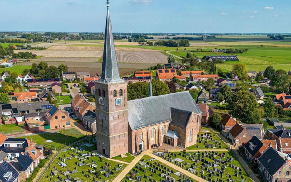 Luchtfoto Sint Maarten kerk en dorp kerkhof huizen bomen vergezicht hallum